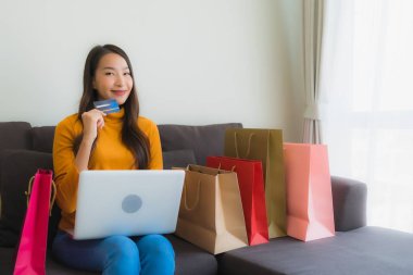 Genç Asyalı kadının akıllı mobili dizüstü bilgisayar kullanan portresi.