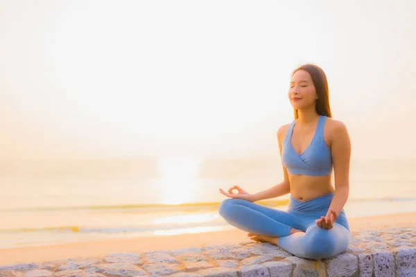 Porträtt ung asiatisk kvinna gör meditation runt havet strand — Stockfoto