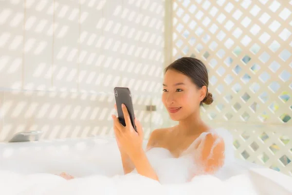 Ritratto giovane donna asiatica utilizzando smart cellulare nella vasca da bagno — Foto Stock