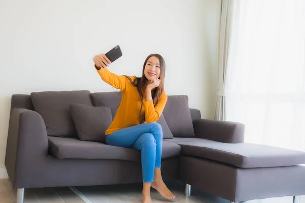 Retrato joven mujer asiática utilizando el teléfono móvil inteligente en el sofá con — Foto de Stock