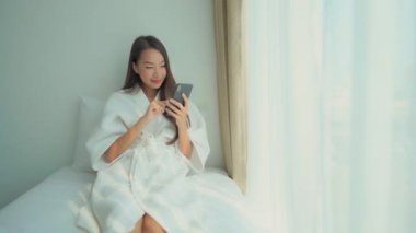 Güzel Asyalı kadının evde akıllı telefon kullandığının görüntüleri.