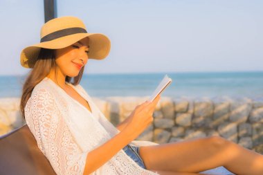 Genç Asyalı kadının portresi deniz kenarında kitap okuyordu.