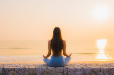 Genç Asyalı kadının portresi, deniz kıyısı okyanusunda meditasyon yapıyor. 
