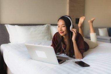 Bilgisayar ve kulaklık kullanan güzel Asyalı kadınların portresi.