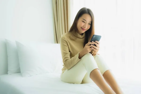 Young asian woman using mobile smart phone on bed — Stock Photo, Image