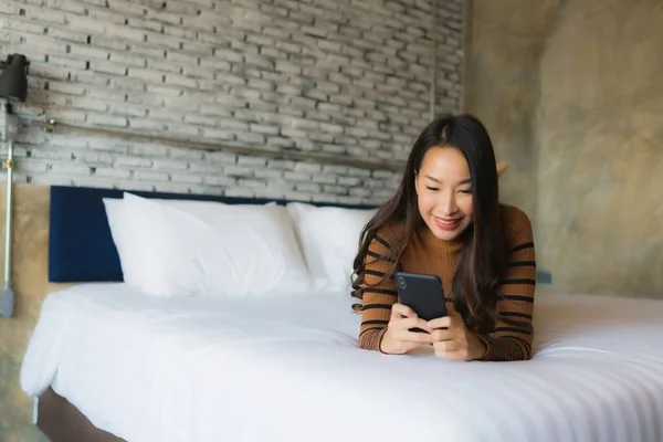 Jeune femme asiatique utilisant téléphone intelligent mobile sur le lit — Photo