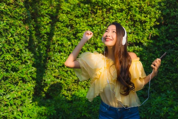 Junge asiatische Frau mit Smartphone mit Kopfhörer für li — Stockfoto