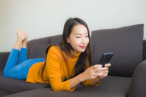 Retrato joven mujer asiática utilizando el teléfono móvil inteligente en el sofá con — Foto de Stock