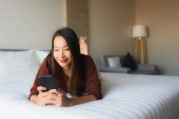 Portret mooie jonge Aziatische vrouwen met behulp van mobiele telefoon op bed — Stockfoto
