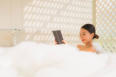 Genç Asyalı kadın küvette kitap okudu.