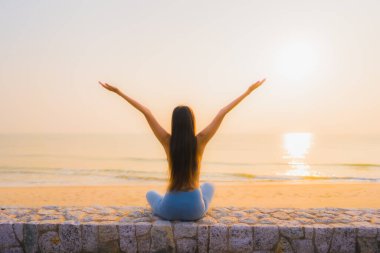 Genç Asyalı kadının portresi, deniz kıyısı okyanusunda meditasyon yapıyor. 