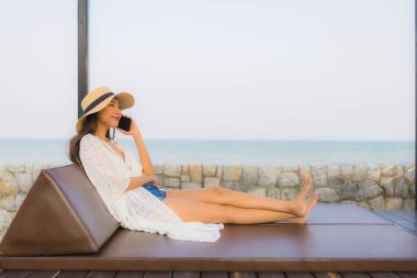 Etrafta akıllı cep telefonu kullanan Asyalı genç bir kadının portresi.