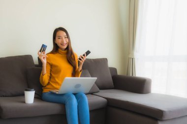 Genç Asyalı kadının akıllı mobili dizüstü bilgisayar kullanan portresi.