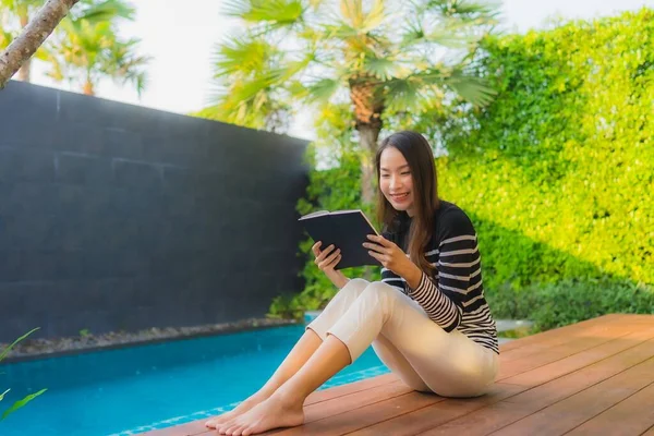 典型人物年轻的亚洲女人在室外游泳池边看书 — 图库照片