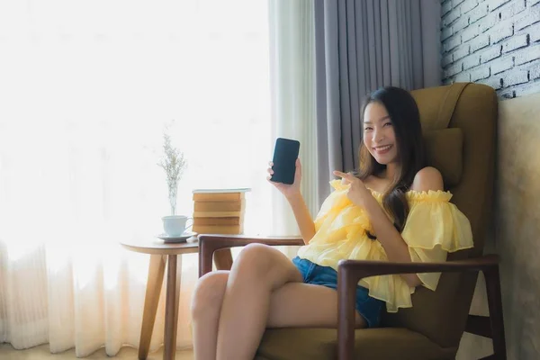 Портрет молодой азиатской женщины с помощью мобильного телефона с чашкой кофе — стоковое фото