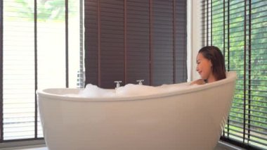 Güzel Asyalı kadının sabun köpüğüyle banyo yaptığı görüntüler.