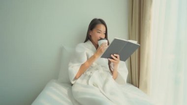 Evde kitap okuyan güzel Asyalı kadının görüntüleri.