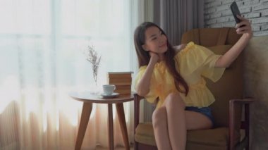 Güzel Asyalı kadının evde akıllı telefon kullandığının görüntüleri.