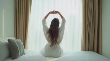 Evde karantina sırasında yatakta dinlenen bornozlu güzel Asyalı kadının görüntüleri.