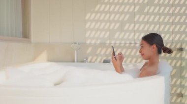 Güzel Asyalı kadının sabun köpüğüyle banyo yaptığı görüntüler.
