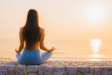 Genç Asyalı kadının portresi, deniz kıyısı okyanusunda meditasyon yapıyor. 