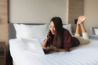 Bilgisayar ve cep telefonu kullanan güzel Asyalı genç kadınların portresi.