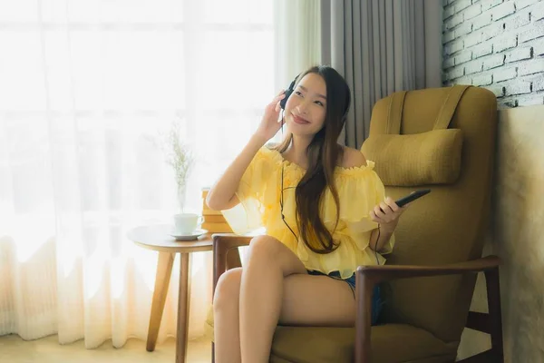 Portret młoda Azjatka siedzieć na krześle słuchać muzyki z telefonu komórkowego — Zdjęcie stockowe