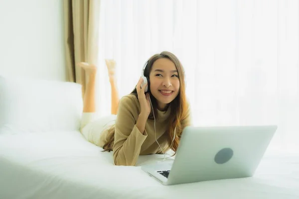 Jonge Aziatische vrouw met behulp van laptop met hoofdtelefoon voor muziek luisteren — Stockfoto