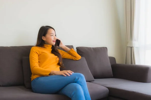 Porträtt ung asiatisk kvinna med hjälp av smart mobiltelefon på soffan med — Stockfoto