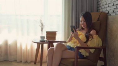Güzel Asyalı kadının evde akıllı telefon kullandığının görüntüleri.