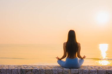 Genç Asyalı kadının portresi, deniz kıyısı okyanusunda meditasyon yapıyor. 