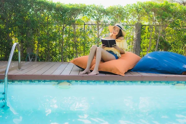 Portrait young asian woman read book around outdoor swimming poo