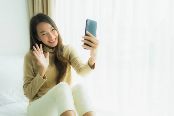 Ung asiatisk kvinna som använder mobiltelefon i sängen — Stockfoto