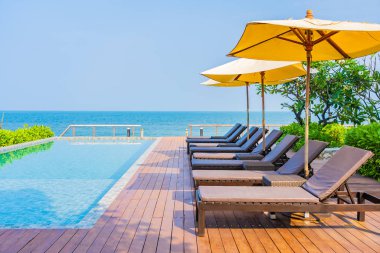 Dışarıda yüzme havuzu etrafında güzel boş bir sandalye şemsiyesi.