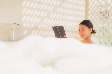 Genç Asyalı kadın küvette kitap okudu.