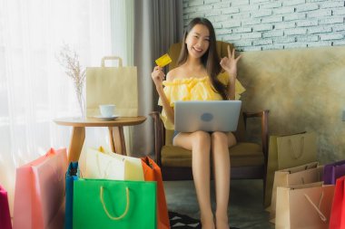 İnternetten alışveriş yapmak için bilgisayarını kullanan Asyalı genç bir kadının portresi.