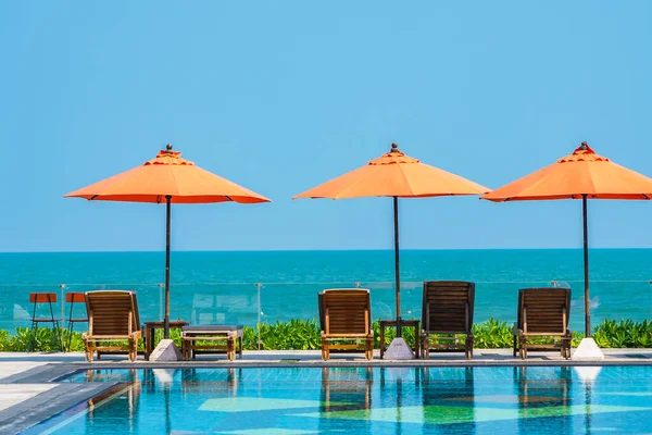 Parapluie et chaise autour de la piscine extérieure près de la mer dans chaud — Photo