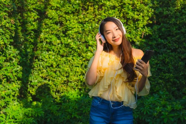 用智能手机配耳机的年轻亚洲女人 — 图库照片