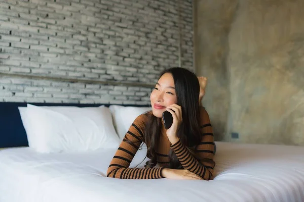 Ung asiatisk kvinna som använder mobiltelefon i sängen — Stockfoto