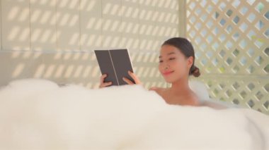 Güzel Asyalı kadının sabun köpüğüyle banyo yaptığı görüntüler.