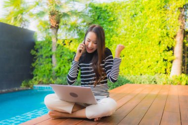 Genç Asyalı kadının akıllı mobili dizüstü bilgisayar kullanan portresi.