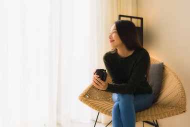 Güzel bir Asyalı kadının portresi. Elinde kahve fincanı, elinde oturuyor.