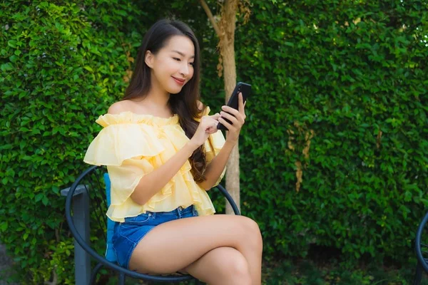 Fiatal ázsiai nő használ okos mobiltelefon körül szabadtéri természet — Stock Fotó