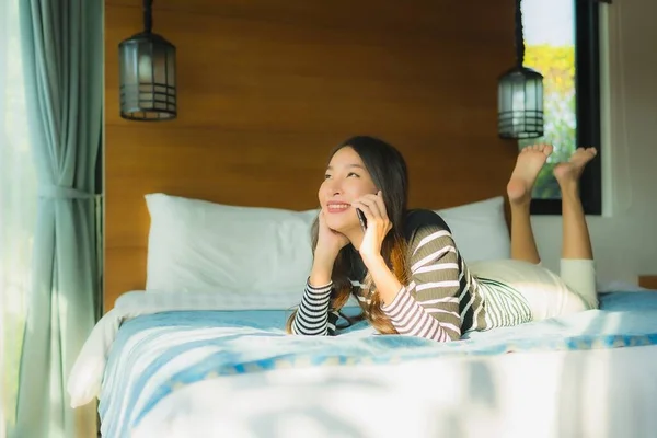 Retrato jovem mulher asiática usando telefone celular inteligente na cama em ser — Fotografia de Stock