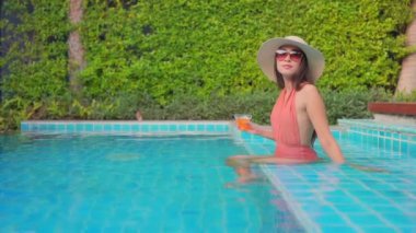 Güzel Asyalı bir kadının oteldeki havuzda dinlenirken çekilmiş görüntüleri.