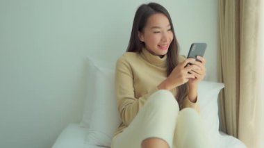 Güzel Asyalı kadının evde akıllı telefon kullandığının görüntüleri.
