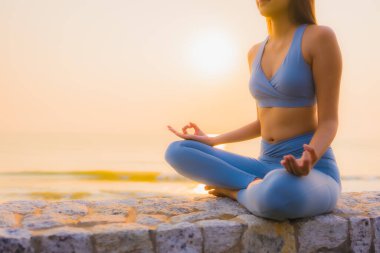 Genç Asyalı kadının portresi, deniz kıyısı okyanusunda meditasyon yapıyor. 