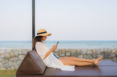 Etrafta akıllı cep telefonu kullanan Asyalı genç bir kadının portresi.