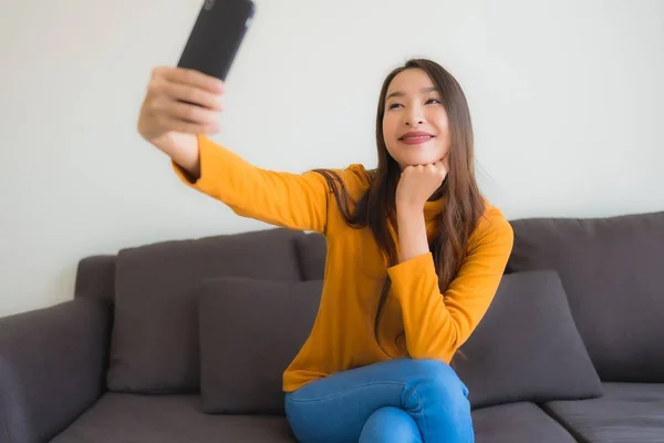 Porträtt ung asiatisk kvinna med hjälp av smart mobiltelefon på soffan med — Stockfoto