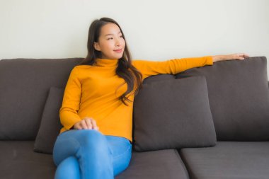 Genç Asyalı kadının mutlu portresi. Kanepede rahatla. 